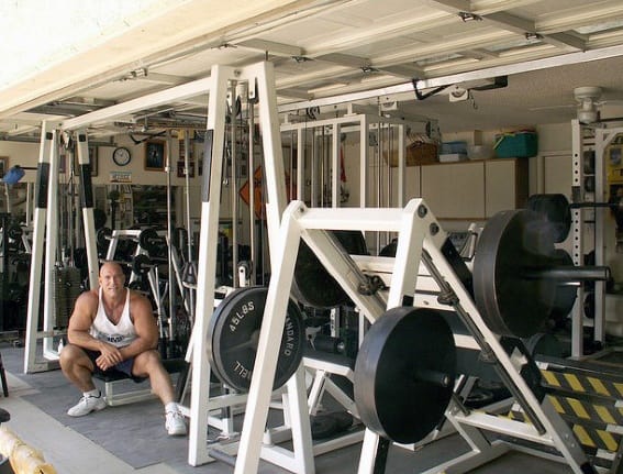 Garage gym fully equipped with weightlifting machines, squat rack, and ample weight plates for bodybuilding.