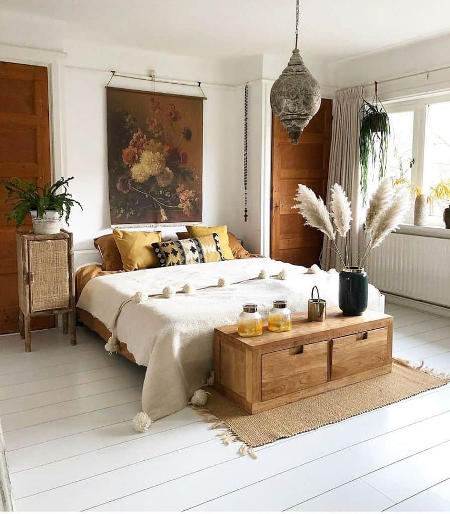 Boho bedroom with natural wood furniture, floral wall art, pampas grass, and hanging lantern.
