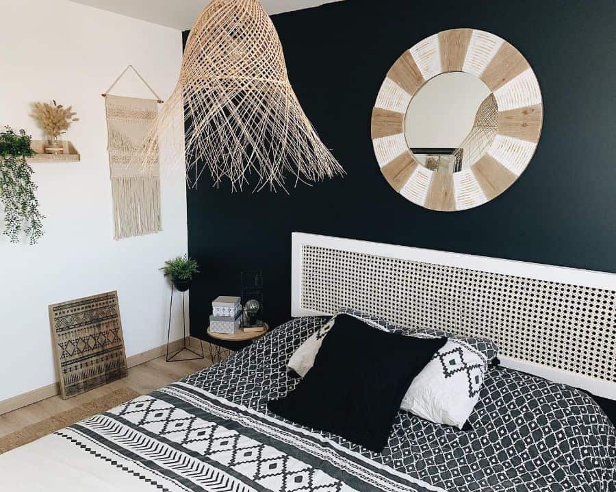 Boho bedroom with black accent wall, rattan pendant light, and patterned bedding.