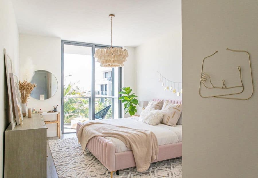 Bright bedroom with a pink bed, decorative chandelier, large window, plants, and modern decor