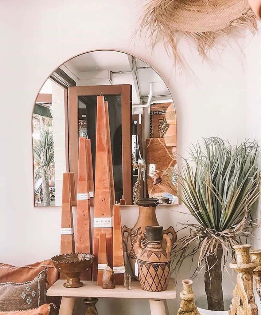 Boho decor with terracotta candles, pottery, and natural elements on a wooden table.