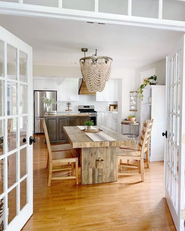 Boho dining room with a rustic wooden table, bench seating, and a beaded chandelier.
