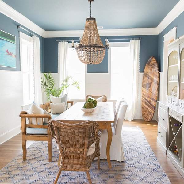 Boho dining room with coastal vibes, a wooden table, wicker chairs, and a beaded chandelier.