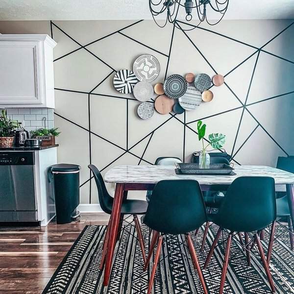 Boho dining room with a marble table, black chairs, and a geometric accent wall.