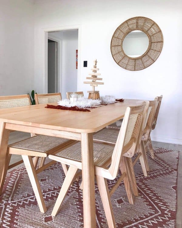Boho dining room with neutral tones, minimalist wooden furniture, and a woven mirror.