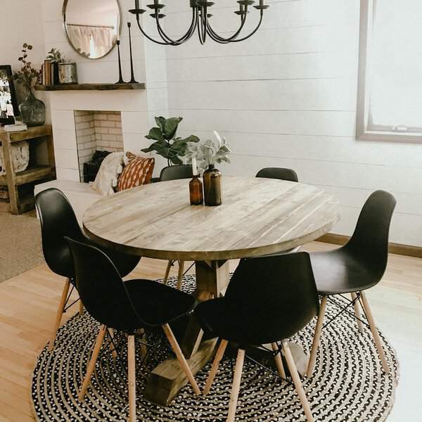 Boho dining room with a rustic wooden table, black chairs, and cozy lighting.