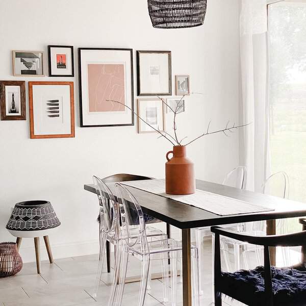 Boho dining room with a dark wood table, ghost chairs, and a gallery wall.