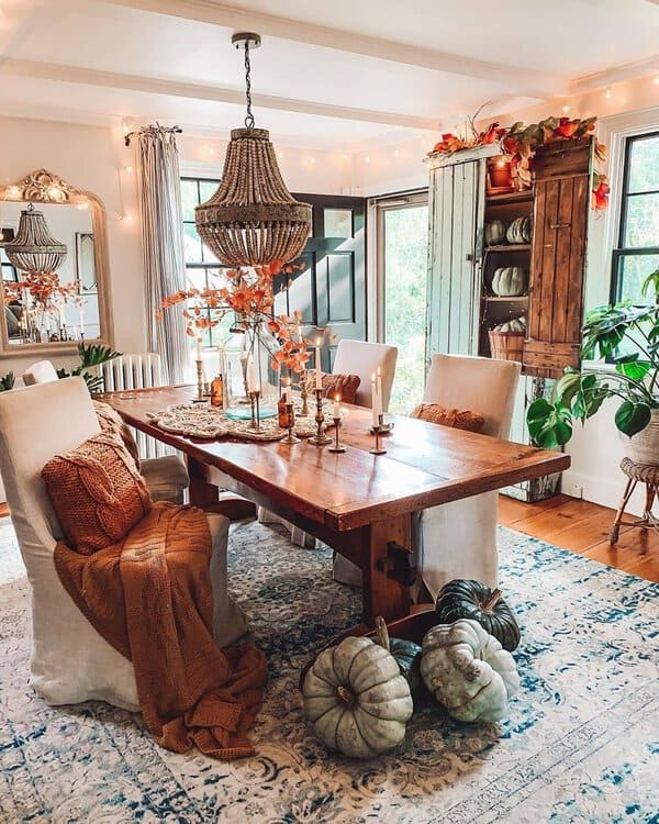 Boho dining room with vintage charm, pumpkins, cozy lighting, and rustic decor.