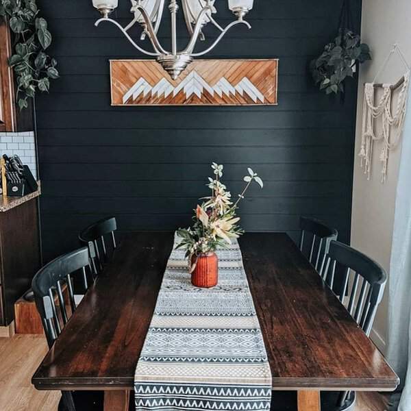 Boho dining room with a dark wood table, black chairs, and a tribal-patterned runner.