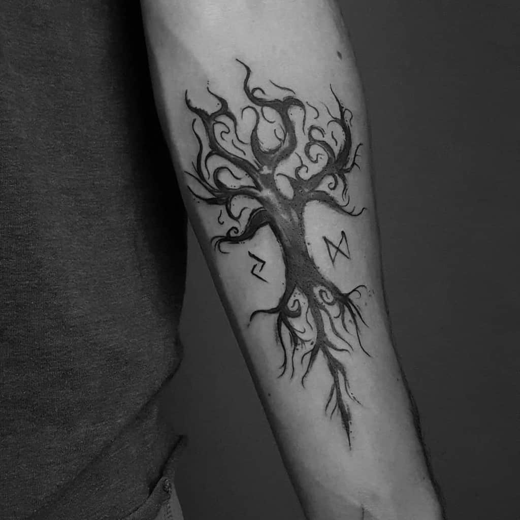 Black and gray Yggdrasil tattoo with swirling branches and roots, adorned with Norse runes, inked on the inner forearm.