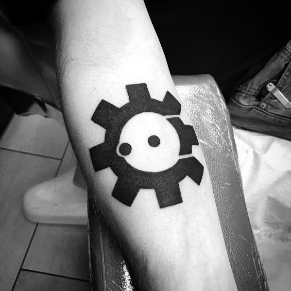 Bold black and white tattoo of the Biohazard Gear logo on the forearm, featuring a cogwheel design with a yin-yang style face in the center.
