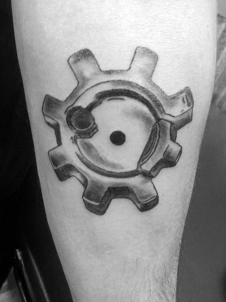 Realistic black and grey tattoo of an AR-15 bolt face on the forearm, featuring intricate shading and depth, symbolizing firearm mechanics and precision.