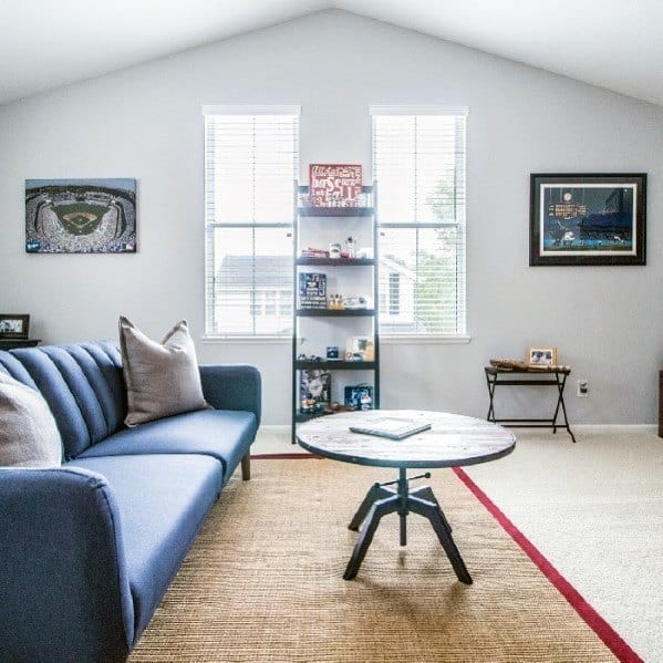 Sports-themed room with blue sofa, round coffee table, display shelf, and framed memorabilia.