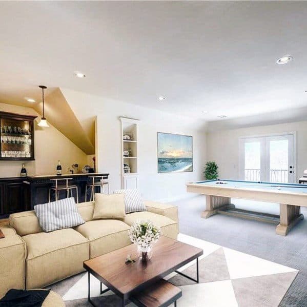 Bright game room with pool table, cozy sofa, home bar, and modern decor.