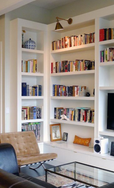 Living room with white bookshelves, books, a chair, a TV, a speaker, and decorative items on display