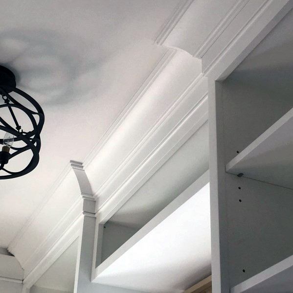Elegant crown molding in a white room with a modern light fixture and a bookcase shelf