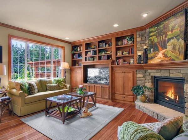 Traditional living room with stone corner fireplace, built-in wooden bookcases, beige sofa, and armchair.