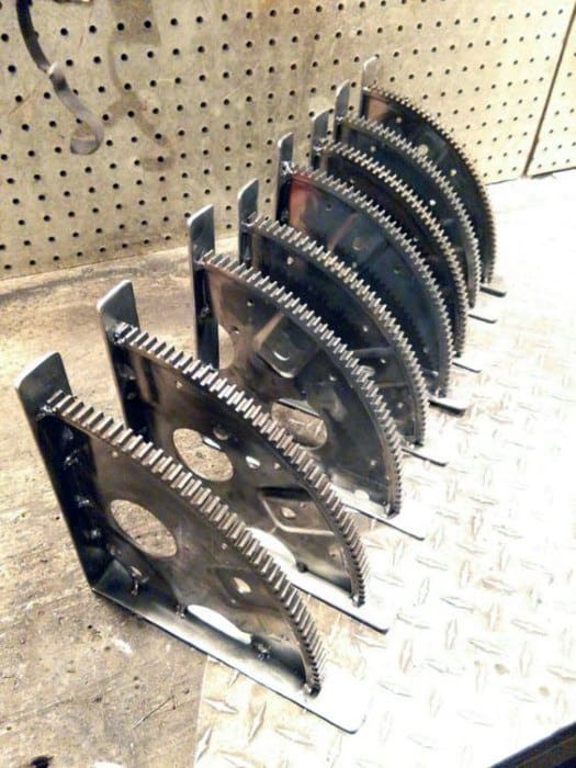 Six metal bookends made from circular saw blades arranged in a row on a diamond-patterned metal surface