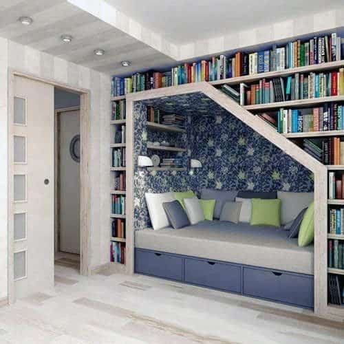 Cozy reading nook with a cushioned bench, bookshelves, and floral wallpaper on one wall