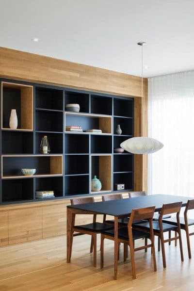 Modern dining room with a wooden bookshelf, black table, four chairs, and a pendant light