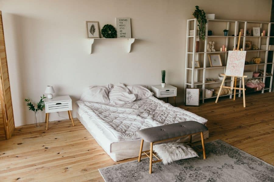 Spacious boho bedroom with white shelving, hardwood floors, and minimalist decor.