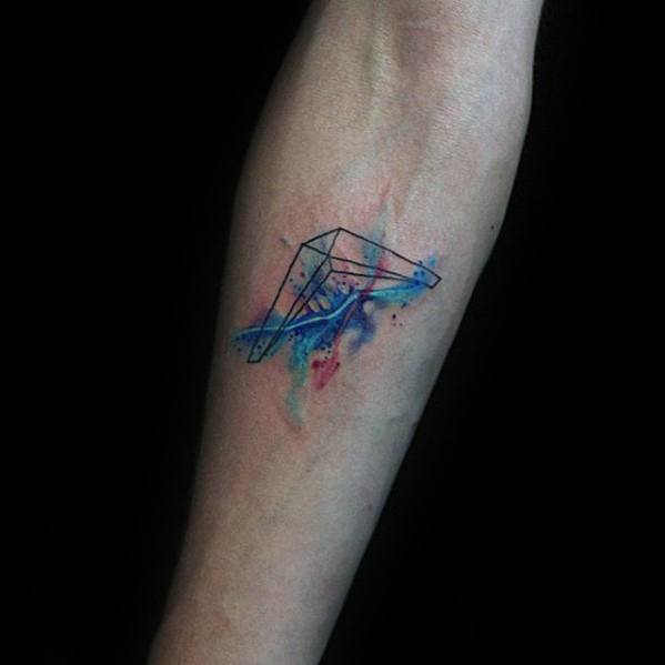 Geometric boomerang tattoo with a vibrant watercolor splash in blue, purple, and pink tones on the inner forearm.