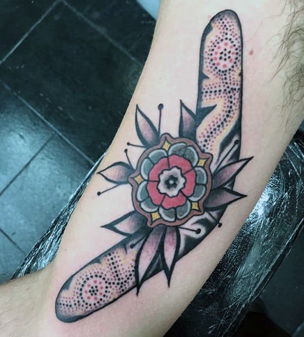 Detailed boomerang tattoo with dotwork patterns and a mandala-style flower at the center, placed on the inner arm.
