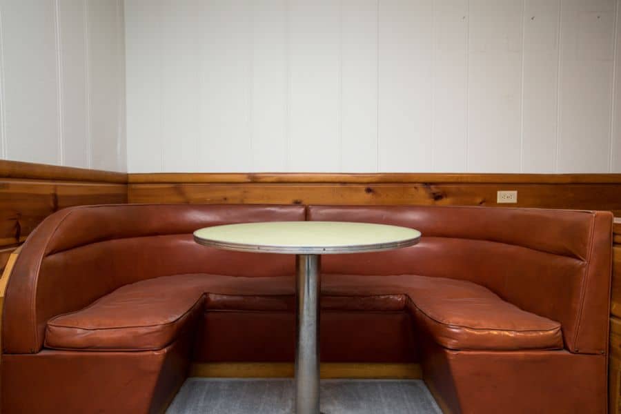 Brown leather booth alcove with a small round table and wood-paneled walls.