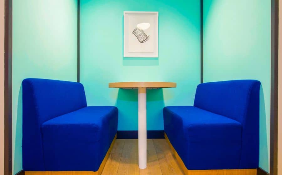 Blue booth seating with round wooden table in a vibrant teal alcove.