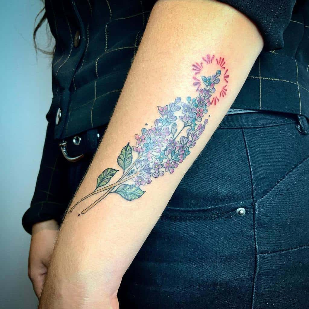 Colorful forearm tattoo of a lilac branch with fine details and a subtle halo effect near the flowers, blending realism with soft shading.