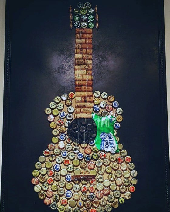 A guitar-shaped collage using corks and bottle caps on a dark background