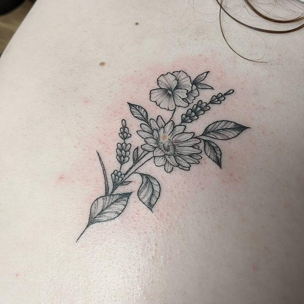 Delicate black and grey floral tattoo featuring a bouquet of daisies, violets, and lavender with fine-line details, creating a soft and elegant design