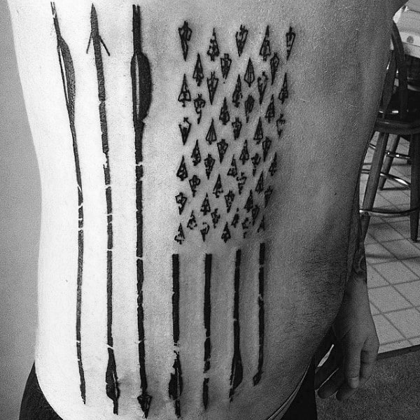 American flag tattoo made of arrows and broadheads, inked on the side of the torso in a bold blackwork style.