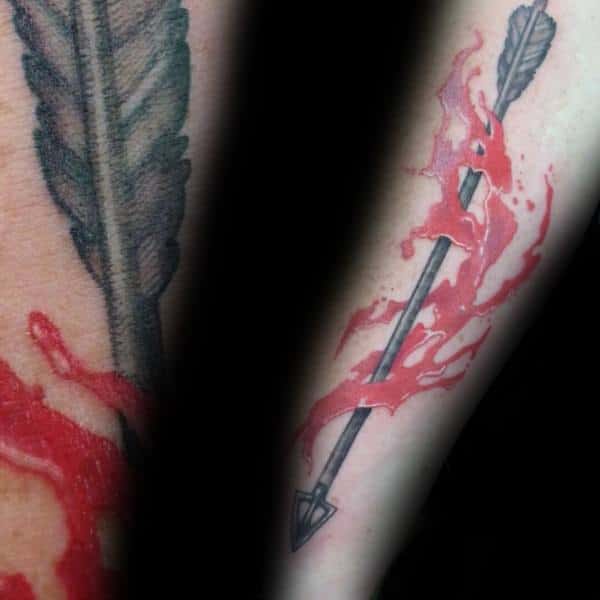 Black and gray arrow tattoo on the arm with dynamic red ink splash, creating a vivid motion and blood-like effect.