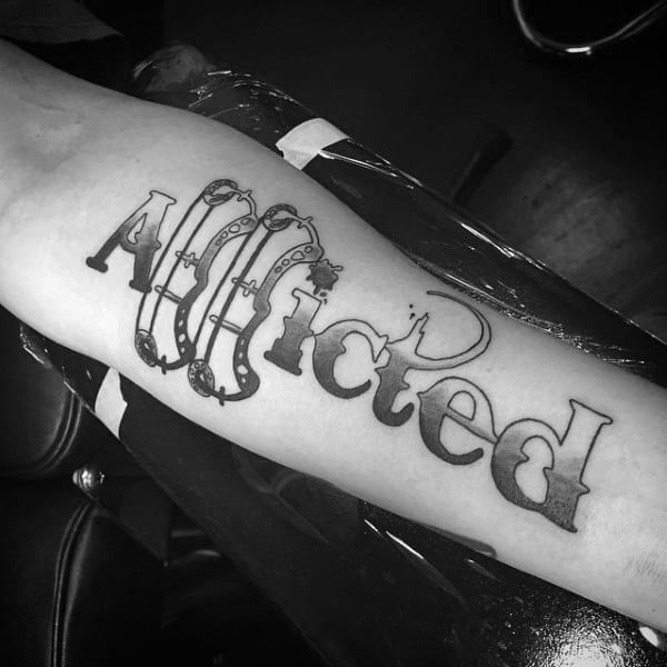 Forearm tattoo of the word Afflicted in bold black letters, with stylized bow and arrow forming the letter A.