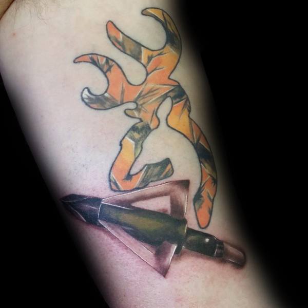 Color tattoo featuring a camouflage Browning deer logo above a realistic broadhead arrow tip piercing through the skin.