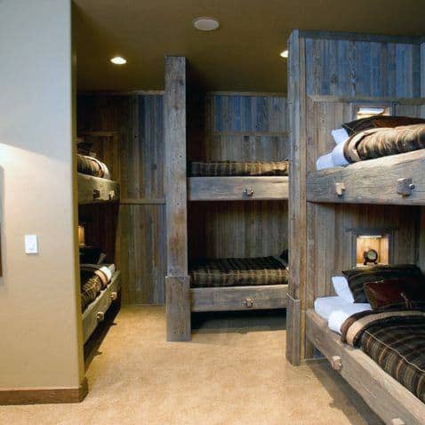Rustic wooden bunk beds with built-in shelves and warm lighting, perfect for a cozy cabin-inspired room