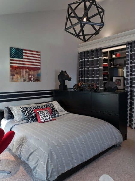 Boy's bedroom with American flag wall art, geometric pendant light, and dark furniture.
