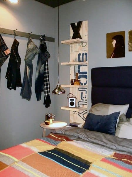 Cozy bedroom with wall art, hanging clothes, a side table, pendant light, and a colorful bedspread