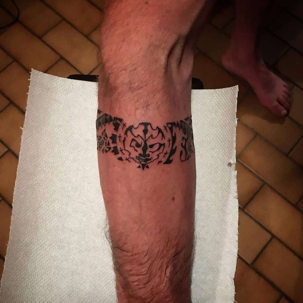 Minimalistic black Tiki tattoo, featuring a symmetrical design with bold lines and a central mask motif