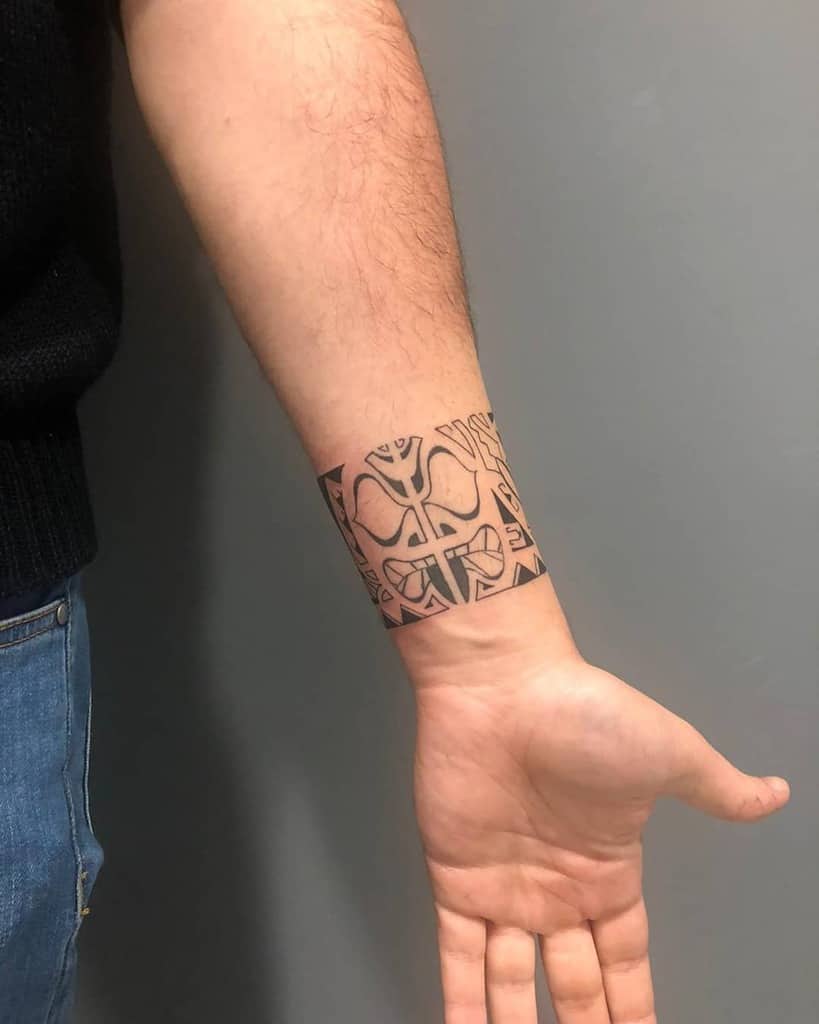 Bold black Tiki tattoo, featuring geometric patterns and symmetrical designs with sharp lines and shapes