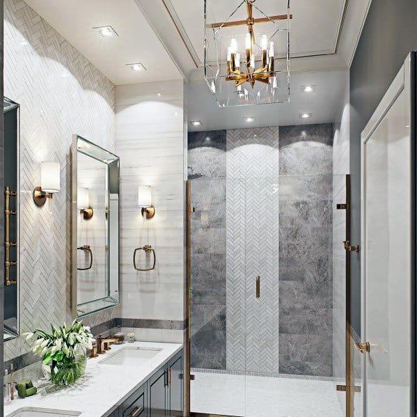 Luxury bathroom with gold chandelier, glass shower, and marble finishes.
