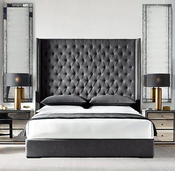 Modern bedroom with tufted gray headboard, brass table lamps, and mirrored decor.