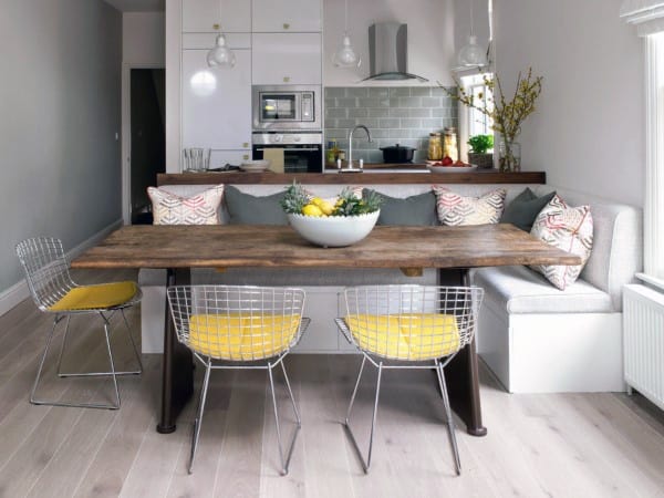 Cozy kitchen nook with a wooden dining table, yellow cushioned chairs, and a bowl of lemons in modern design and neutral colors