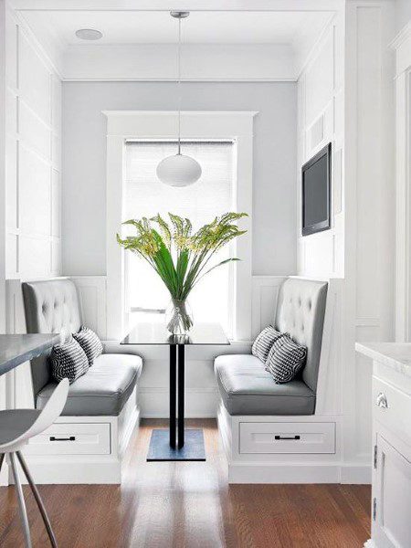 Sleek nook featuring a black table, gray cushioned benches, plant centerpiece, and wall-mounted TV