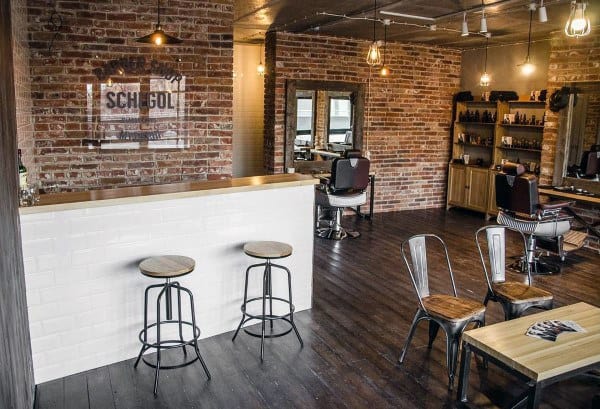 Barbershop with exposed brick walls, hardwood floors, and a cozy café-style counter area.