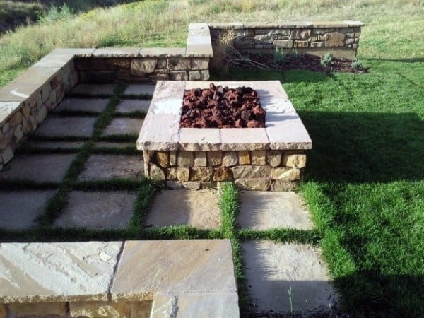 Stone fire pit on grass with a cozy paved stone seating area