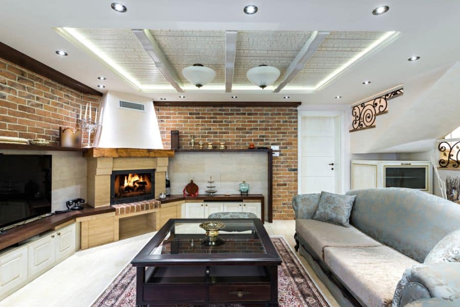 Cozy living room with a brick accent wall, fireplace, comfortable sofas, and a glass-top coffee table