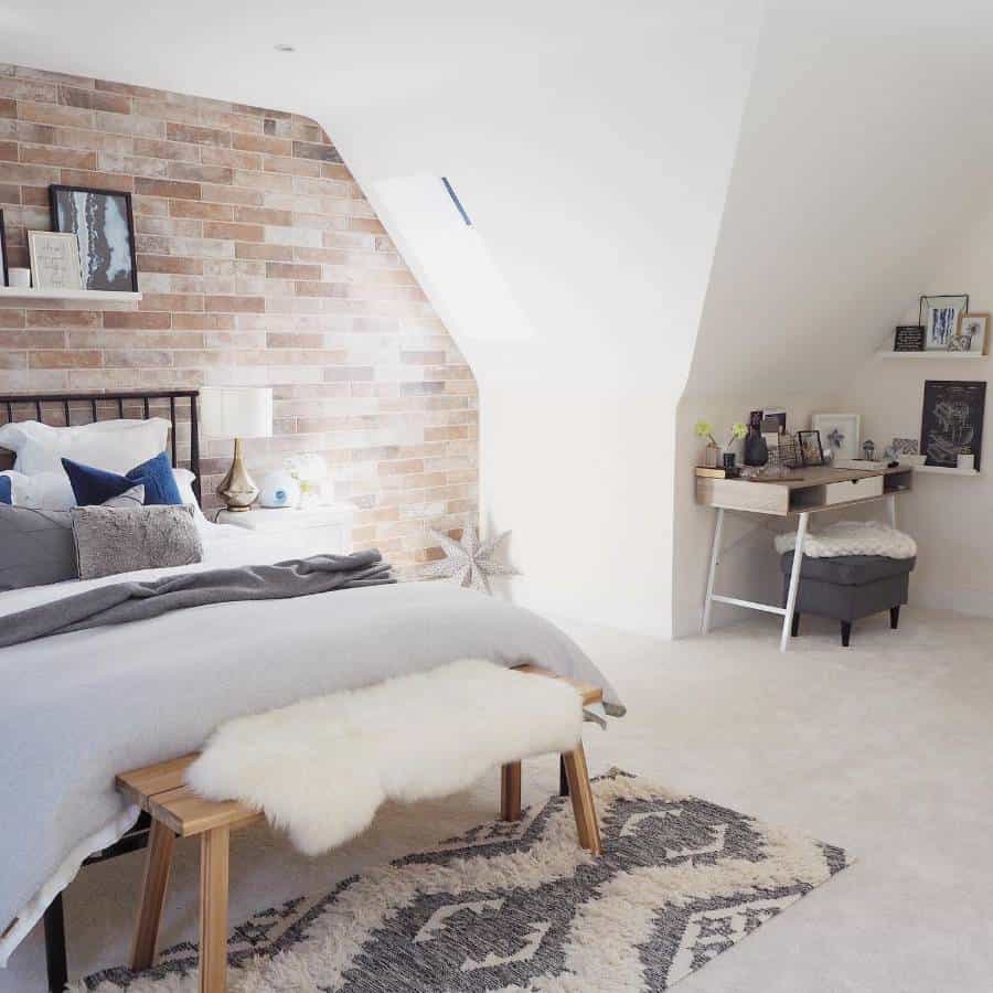Cozy attic bedroom with an accent wall, bed, wooden bench, small desk, and bright window light