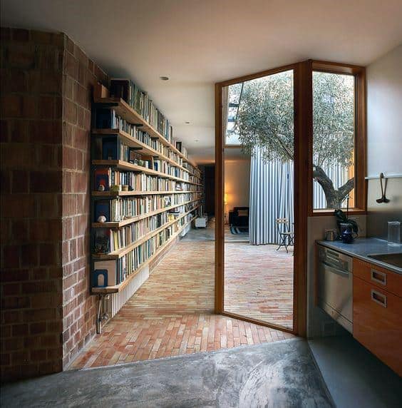 Modern interior with a bookshelf, open glass doors, and a tree in a courtyard